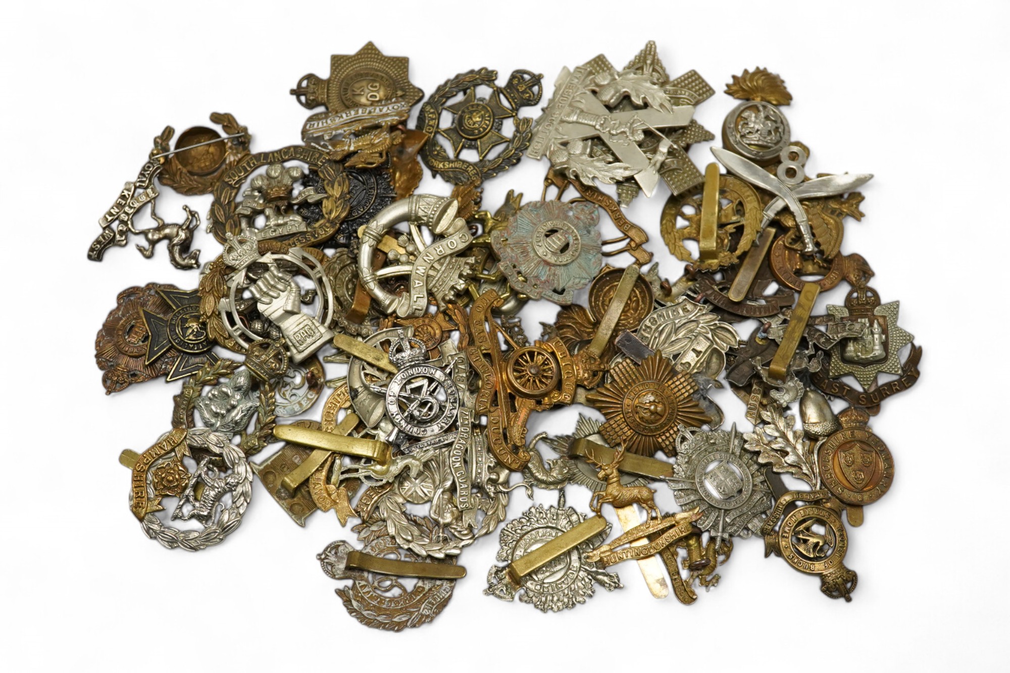 Sixty military cap badges, including; the Hampshire regiment, the South Lancashire Regiment, Prince of Wales Volunteers, the Tyneside Scottish Regiment, the Royal Artillery, the Norfolk Regiment, the Army Ordinance Corps